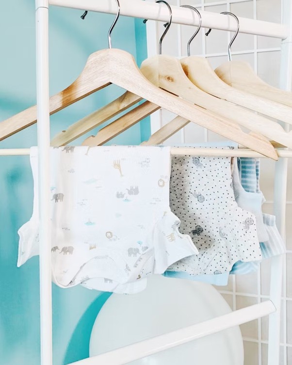Assorted infant garments and baby sleepwear neatly arranged on hangers in a retail store.