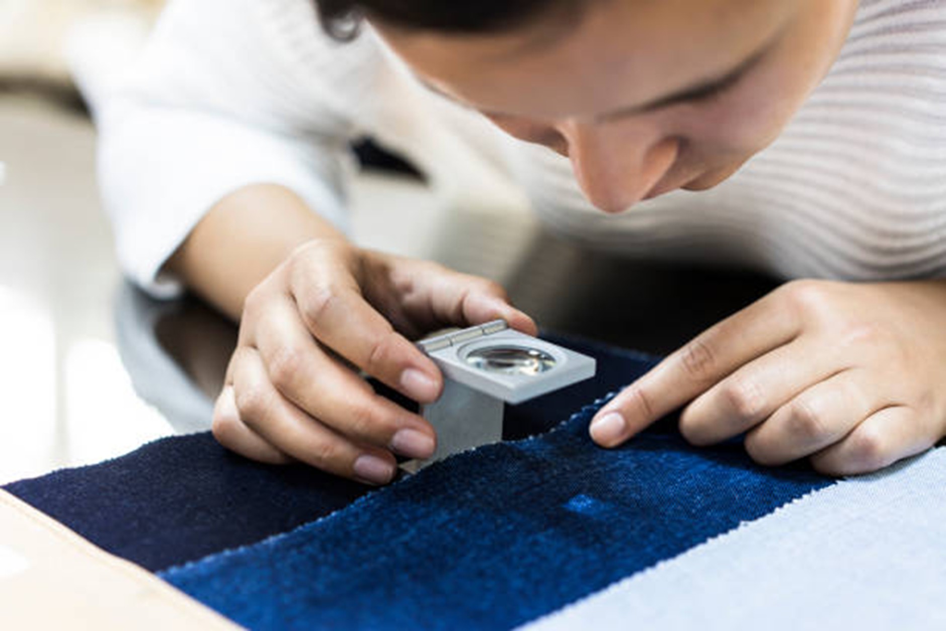 Quality inspector examining fabric texture closely during textile quality control process in a garment factory in India.”