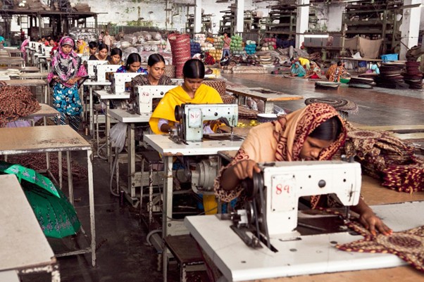 Women stitching garments in an Indian textile factory for newborn and infant apparel production.