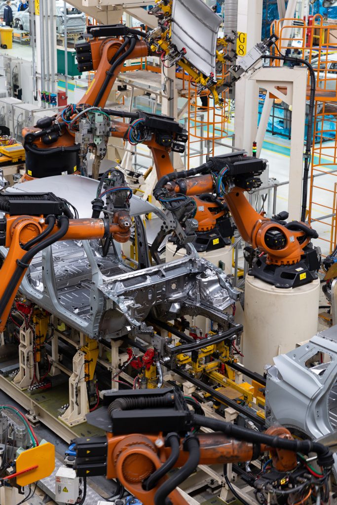 Automotive production line with robotic arms operated by Indian manufacturers for industrial goods export.