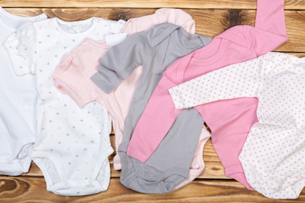 Assorted baby bodysuits in pastel colors produced by verified Indian babywear manufacturers for UK brands