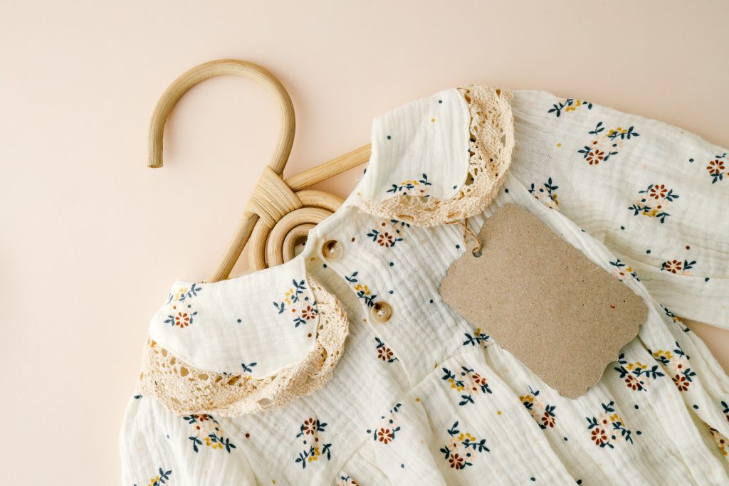 Organic cotton baby dress with floral print made by Indian clothing manufacturers. A close-up of an organic cotton baby dress with delicate floral detailing, showcasing the craftsmanship and fabric quality offered by Indian clothing manufacturers for infant apparel lines.