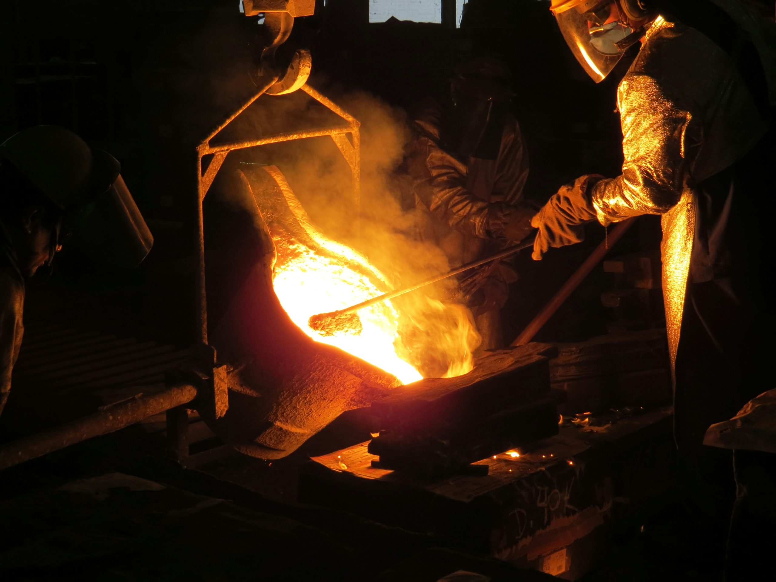 Foundry workers conducting metal casting operations at a casting manufacturers facility. The image captures trained workers managing molten metal and pouring it into prepared moulds inside an active foundry. It highlights the operational discipline, safety protocols, and process expertise that define professional casting manufacturers serving global industrial supply chains.