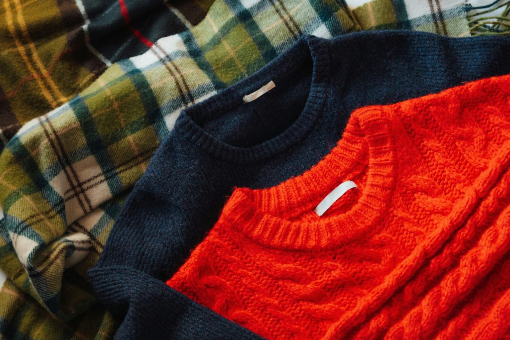 children’s apparel production, infant and children’s garment manufacturing. Flat-lay of children’s knit sweaters showcasing kidswear manufacturing focused on organic materials, consistent quality, and regulated children’s apparel production standards.