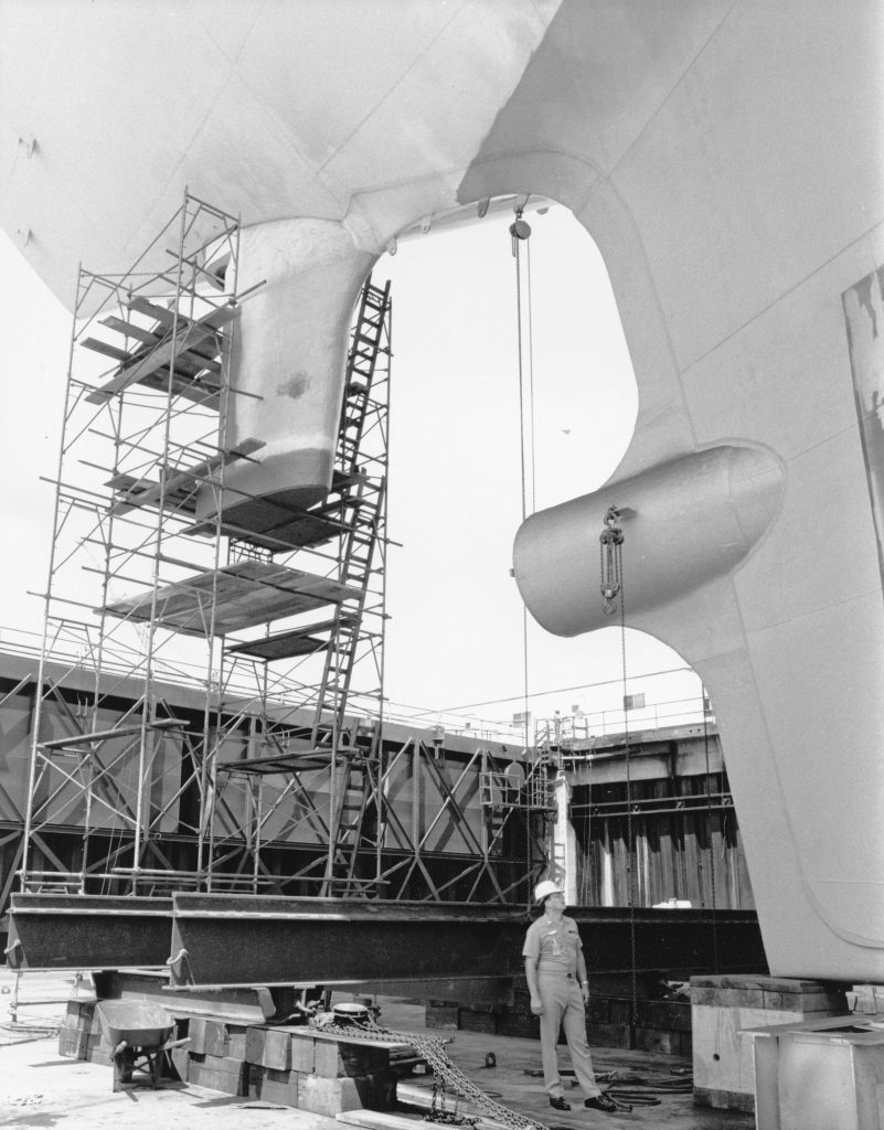 Ship hull block assembly supporting procurement logistics and sourcing operations in shipyards. This image shows a partially assembled ship hull block supported by scaffolding inside a shipyard, illustrating modular construction methods that strengthen supply chain management, streamline procurement logistics, and improve coordination across sourcing operations.