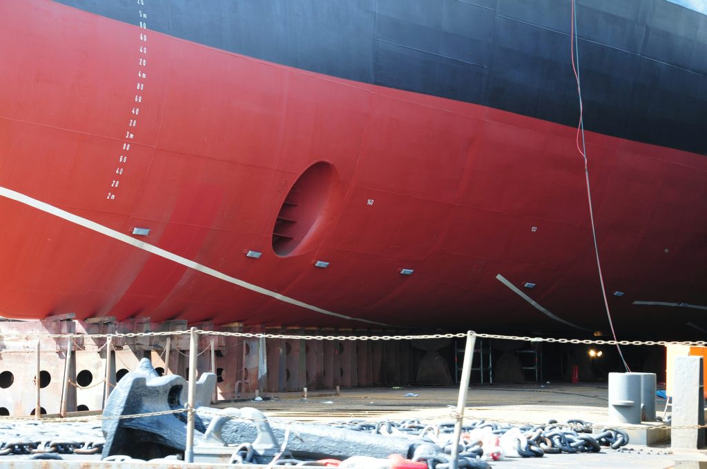 Finished ship hull prepared through integrated supply chain management and sourcing operations. The lower section of a finished ship hull displays marine-grade protective coatings and waterline markings, reflecting final-stage shipyard processes where supply chain management, procurement logistics, and sourcing operations converge to ensure compliance and long-term performance at sea.